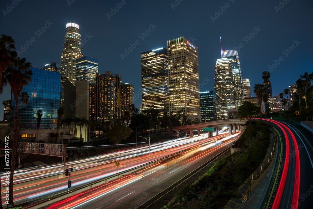 Scene of downtown Los Angeles at night, illuminated by the headlights of cars driving