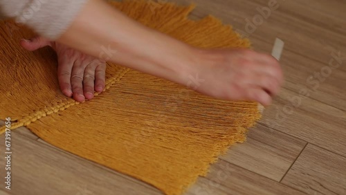 a girl weaves macrame in the form of a large leaf in a bright room. women's hands weave macrame. macrame in the video of a large sheet hanging on the wall.