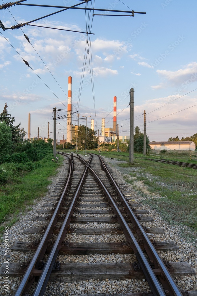Scenic view of an industrial complex featuring multiple train tracks and power lines