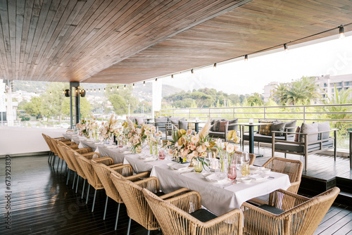 Long festive table on the restaurant terrace with panoramic views of the green park and houses