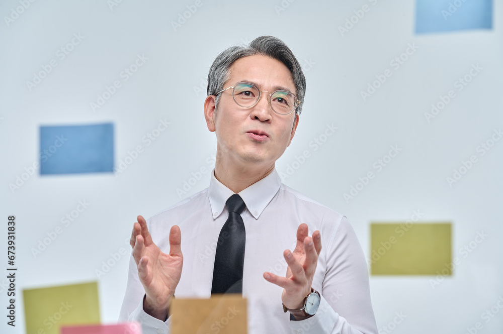 The businessman is standing on the glass wall of the office, looking at the paper attached, thinking about planning and strategies. The businessman is standing on the glass wall of the office, looking at the paper attached, thinking about planning and strategies.