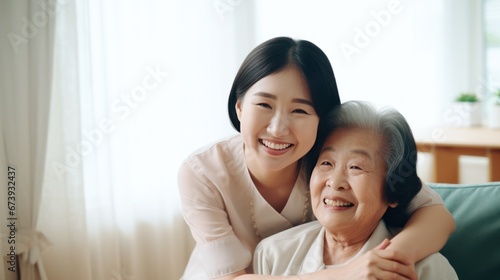 Asian Nurse hugging elderly patients during visit at home
