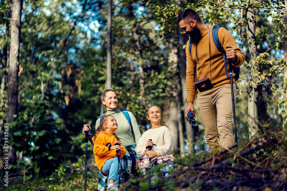 Smiling family of four exploring nature while hiking in forest. Smiling family of four exploring nature while hiking in forest.