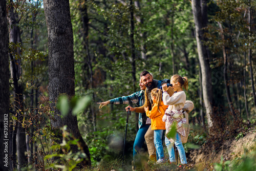 Smiling family of four exploring nature while hiking in forest. © Zoran Zeremski