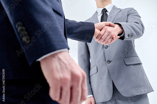 Two men in suits are shaking hands.