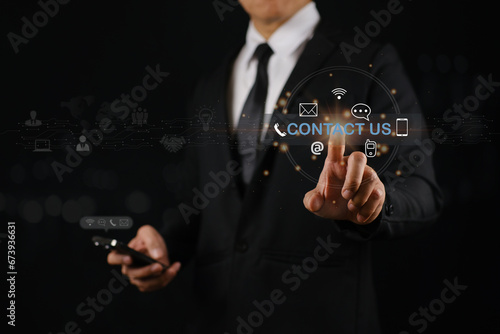 Businessman using smartphone and touching on virtual screen contact icons example email, phone, chat, wifi on black background. concept of contact us or customer support hotline people connect.