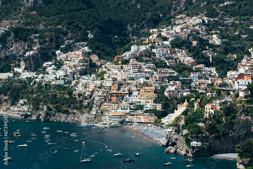 Amalfi Sea Coast with Umbrellas, people swim, and Yachts. Clean and blue sea where to swim. Photo for tourism and summer background. Concept of vacation and beach life in the open air 
