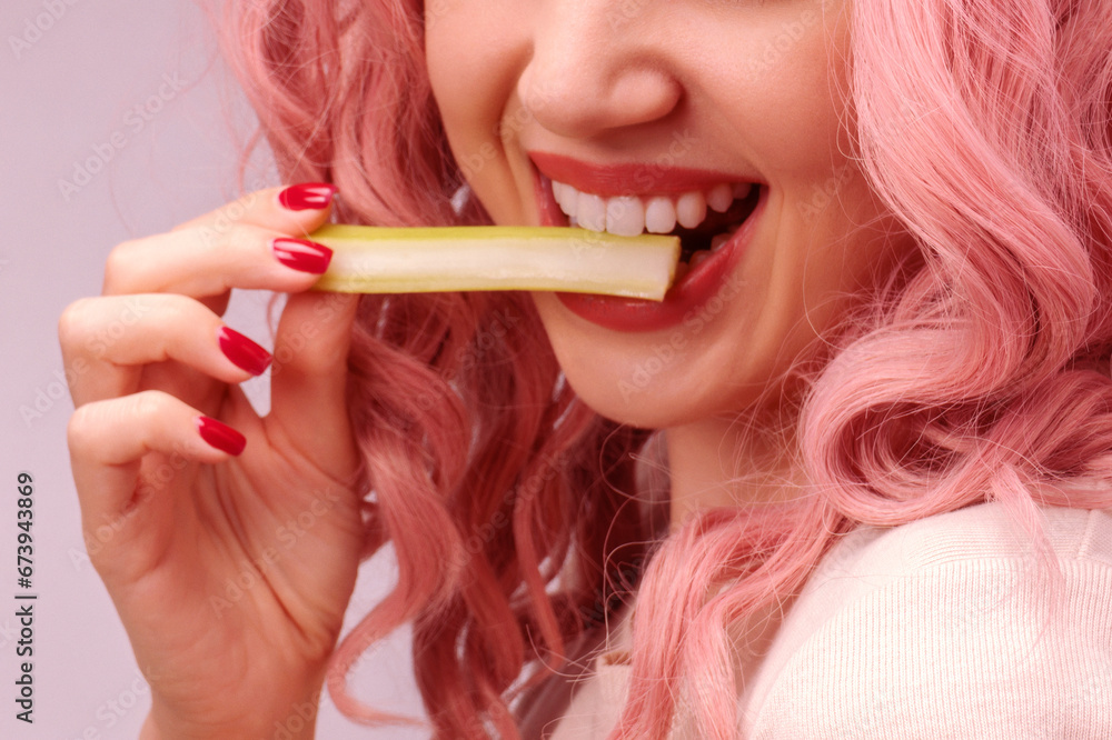 Celery sticks in a woman hand. Woman with pink curly hair is eating celery. Celery sticks in a woman hand. Woman with pink curly hair is eating celery.