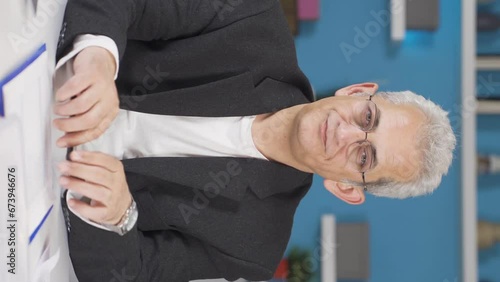 Vertical video of Home office worker man looking smugly at camera. photo