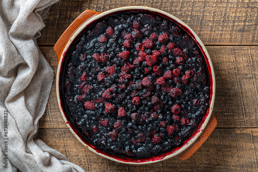 Blueberry and raspberry pie in a ceramic dish on black background, closeup, top view Blueberry and raspberry pie in a ceramic dish on black background, closeup, top view