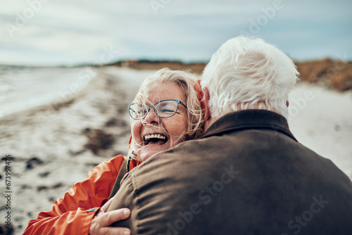 Senior couple hugging on winter beach photo