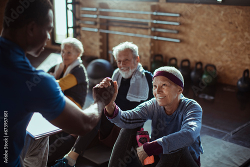 Smiling senior woman working out with friends in gym photo