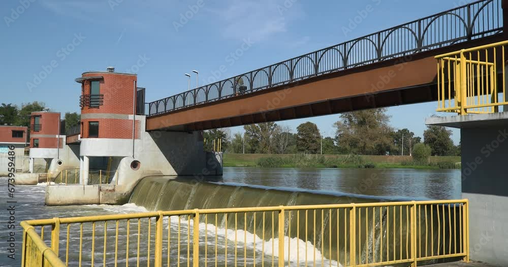 Cyclist riding over a weir above a river on a sunny summer day Cyclist riding over a weir above a river on a sunny summer day