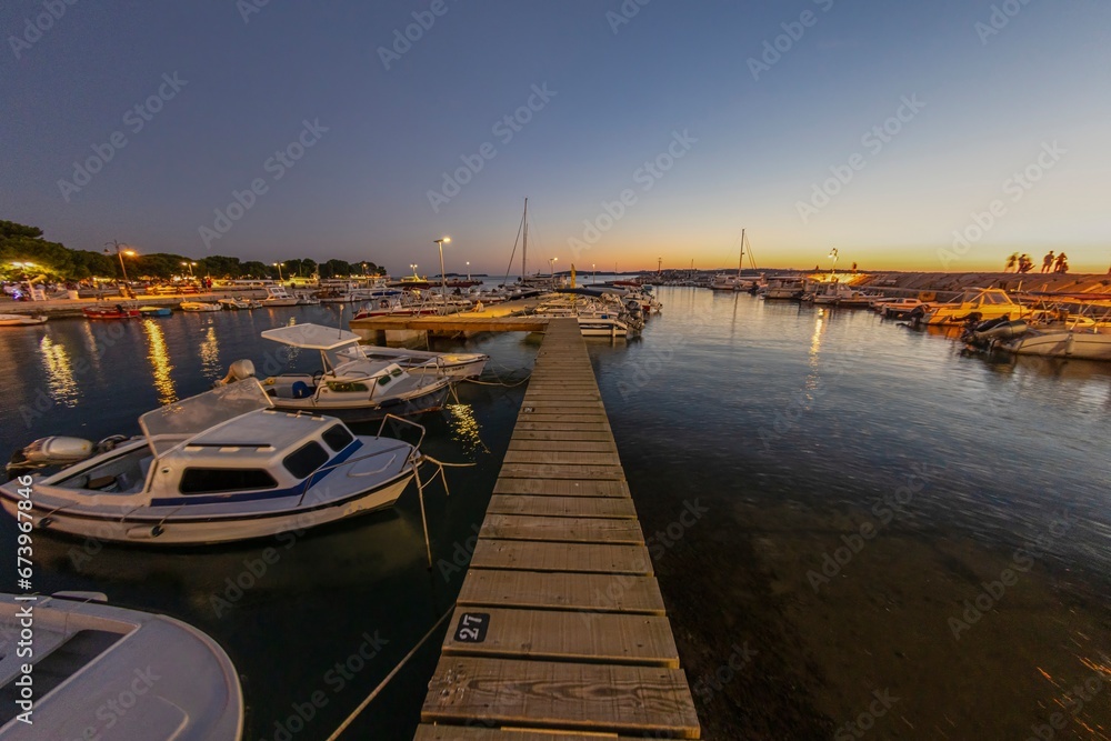 Sunset in the harbor of the Croatian coastal village of Fazana over a jetty for boats in summer evening