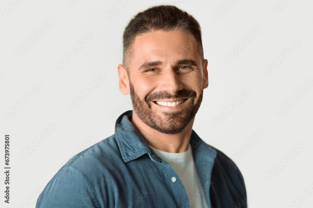 Handsome middle aged bearded man confidently posing against white wall Handsome middle aged bearded man confidently posing against white wall