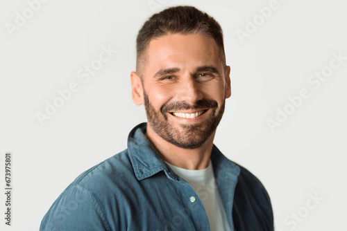 Handsome middle aged bearded man confidently posing against white wall