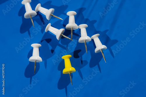 White pushpins and  one yellow on blue.