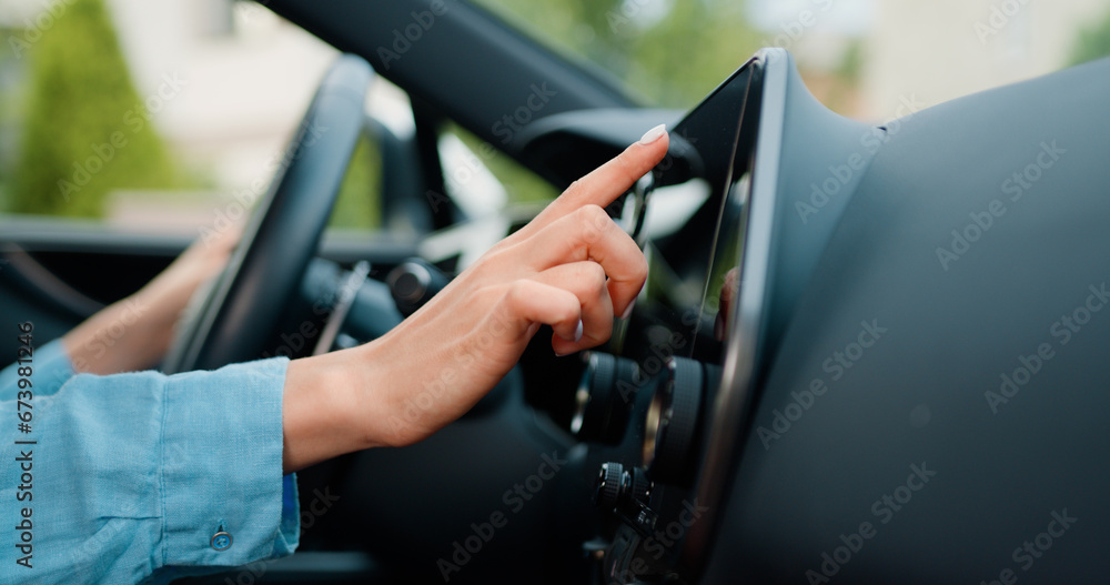 Close up shot hand of woman using touch screen in car setting up the navigation gps application on the touchscreen console.