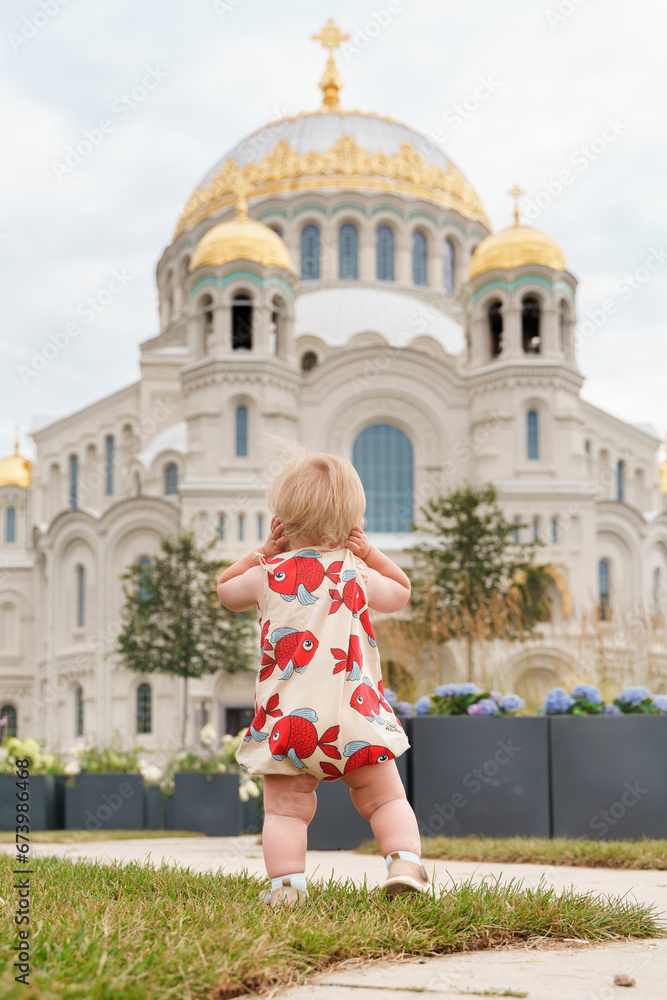 Little child toddler on the background of the Kronstadt Naval St. Nicholas Cathedral