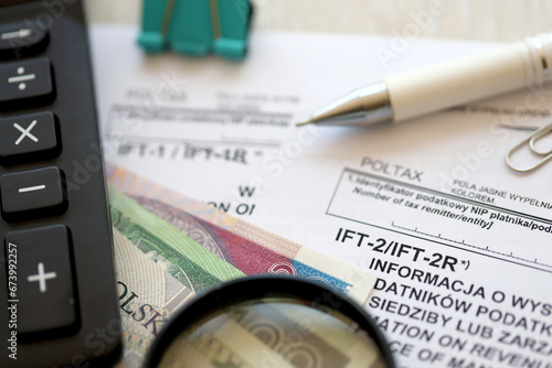 Information on revenue income derived by legal persons and non residents IFT-2, IFT-2R, IFT-1, IFT-1R form on accountant table with pen and polish zloty money bills close up photo