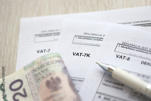 Declaration for tax on goods and services VAT-8, VAT-7K, VAT-7 form on accountant table with pen and polish zloty money bills close up