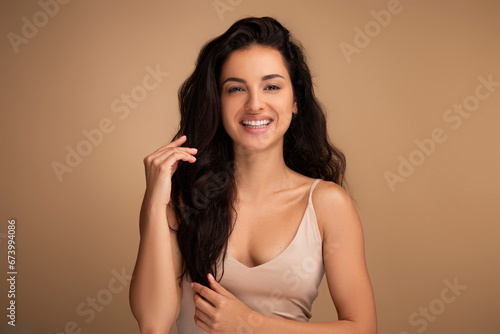 Happy brunette woman touching her beautiful long hair photo
