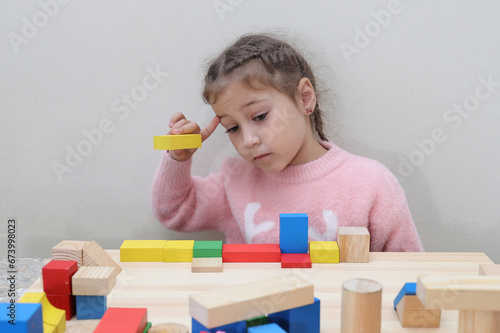 Caucasian preschool girl playing at a table with wooden cubes