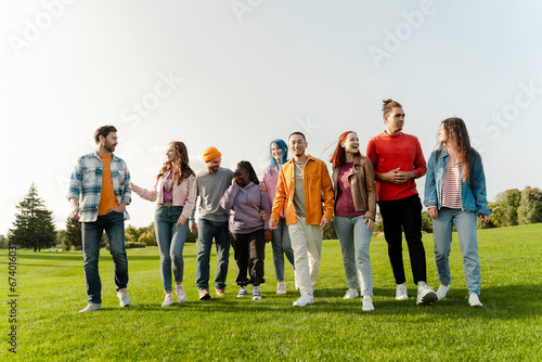 Group portrait of positive diversity friends  hipsters  wearing colorful clothes  walking in park