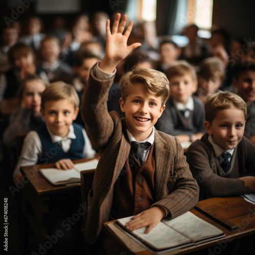 student at a desk in a school class raises his hand  child  smart kid  children  study  learning  classroom  knowledge  lesson  pupil  schoolboy  boy  uniform  european  tie  smile  portrait  face