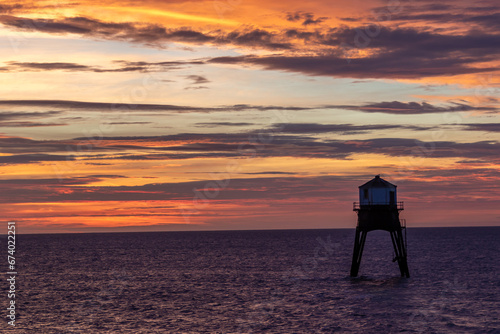 sunrise over a old lighthouse in the sea, Dovercourt low lighthouse, built in 1863 and discontinued in 1917 and restored in 1980 the 8 meter lighthouse is still a iconic sight, October 2023 photo