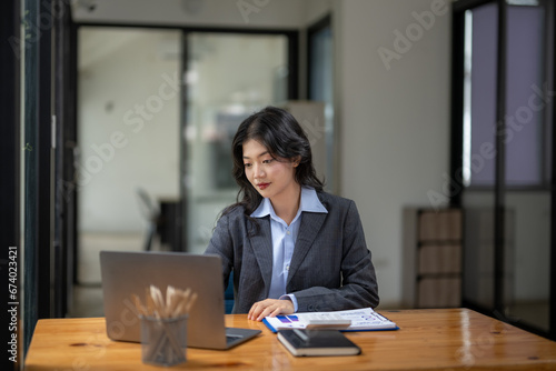 Asian businesswoman sitting and working on laptop. Thinking, planning and focusing on the task.