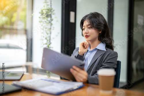 Business woman sitting and working using tablet to check news, information, marketing plan © Wasana