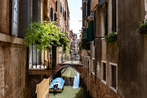 Scenic canal with bridge and old buildings with potted plants in Venice, Italy
