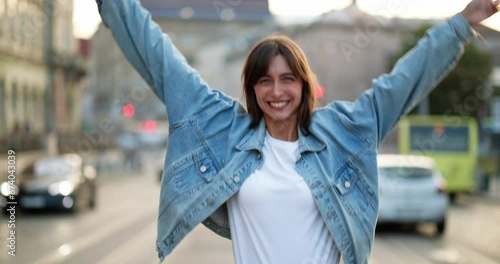 Beautiful woman in jeans jacket walking along the street with traffic.