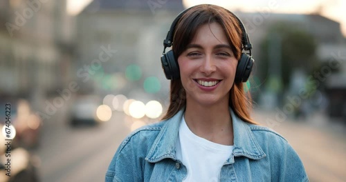 Young woman putting on her headphones and smiling, looking at camera.