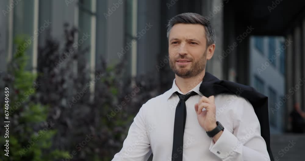Relaxed businessman leaving office building, holding jacket over his shoulder. Relaxed businessman leaving office building, holding jacket over his shoulder.