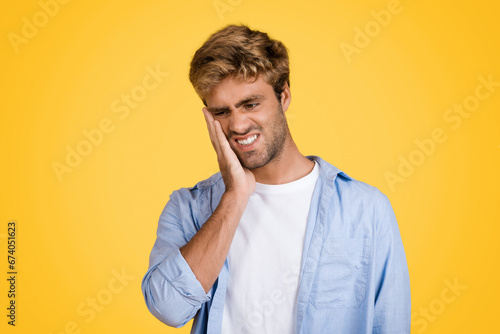 Quadro su tela European man with toothache, touching cheek, yellow background