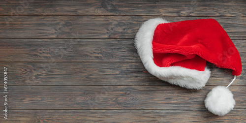 Santa Claus hat on dark wooden background. Top view, long banner with copy space