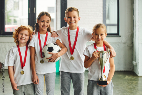 Konstfotografi joyous little boys and girls with medals smiling at camera and holding trophy an
