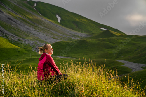 Wallpaper Mural Eine junge Frau (Wanderin) sitzt im im Graß auf einer Alm in den Allgäuer Alpen und genießt den Sonnenuntergang Torontodigital.ca