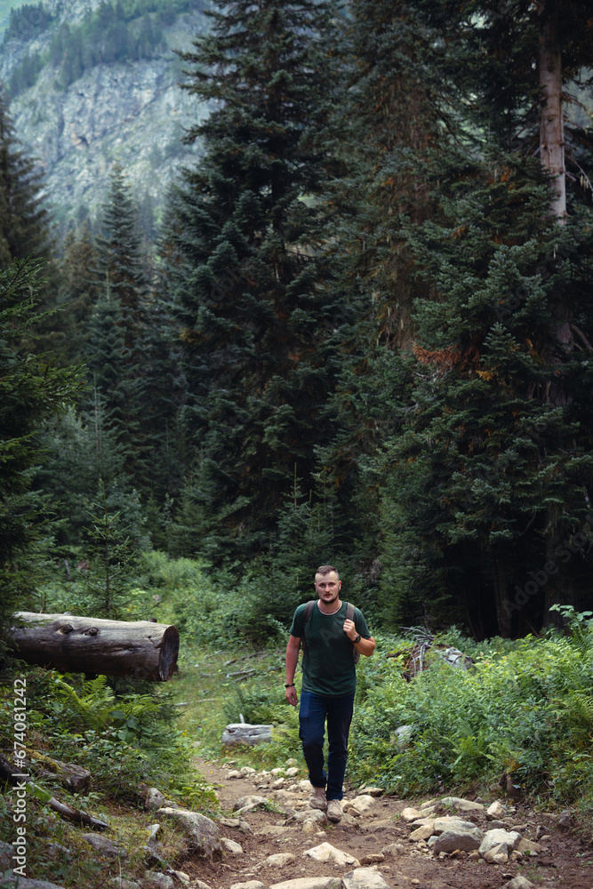Male hiker with retro backpack. A tourist walks along a mountain path in the middle of the forest. Front view. A gloomy summer day. Georgia. the way to the Shdugra waterfall Male hiker with retro backpack. A tourist walks along a mountain path in the middle of the forest. Front view. A gloomy summer day. Georgia. the way to the Shdugra waterfall