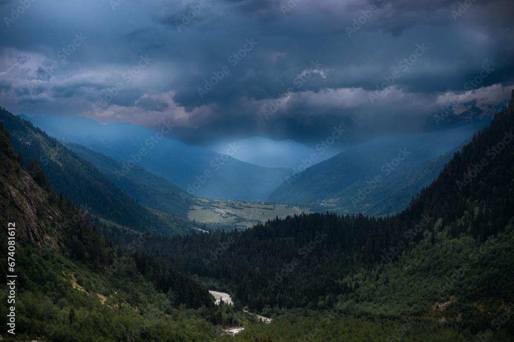 Distant view, valley among high Caucasian mountains, summer evening, dramatic rain clouds. way to Shdugra waterfall, Mazeri, Svaneti, Georgia