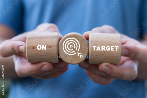 Man holding wooden cylinders with target icon and sees inscription: ON TARGET. On target business concept. Objective marketing. Successful accurate business goals.