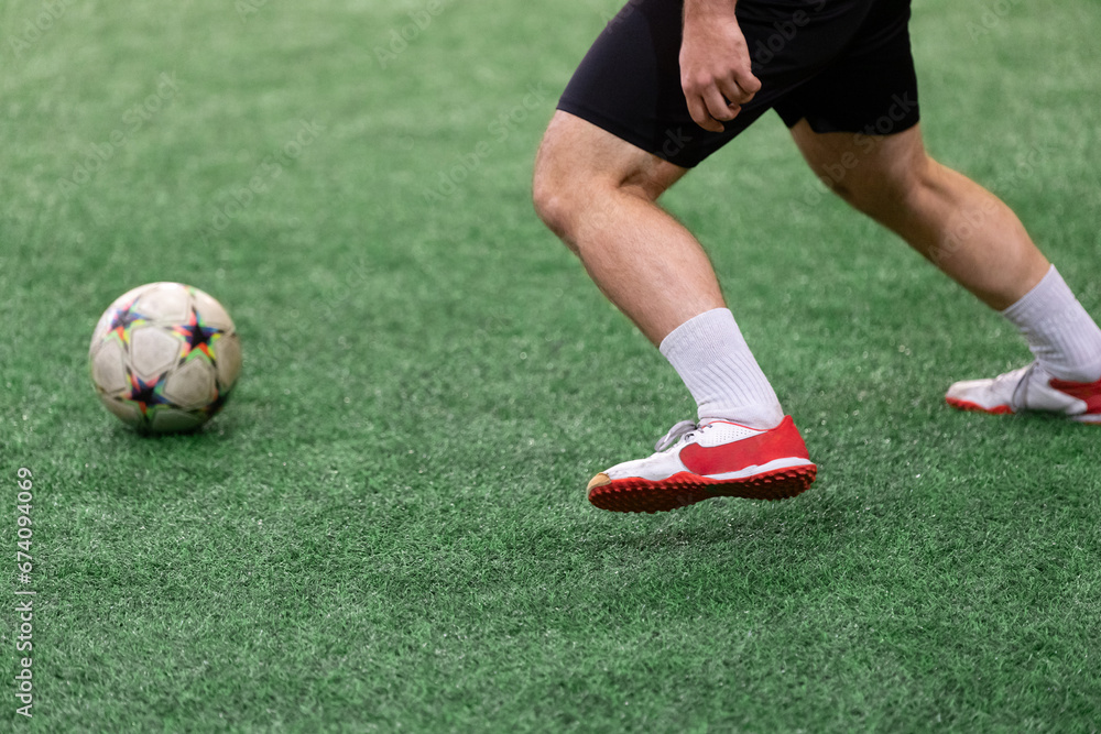 Football Futsal ball and man player legs on artificial grass field indoors. Football Futsal ball and man player legs on artificial grass field indoors.
