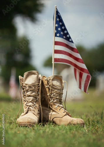 Old military combat boots against American flag in the background. Memorial Day or Veterans Day, sacrifice concept.