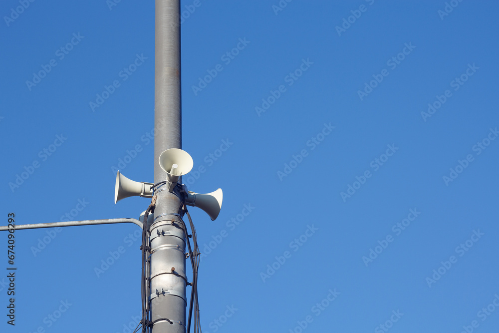 Megaphones on a metal pole against the blue sky. System to alert people. Copy space. Megaphones on a metal pole against the blue sky. System to alert people. Copy space.