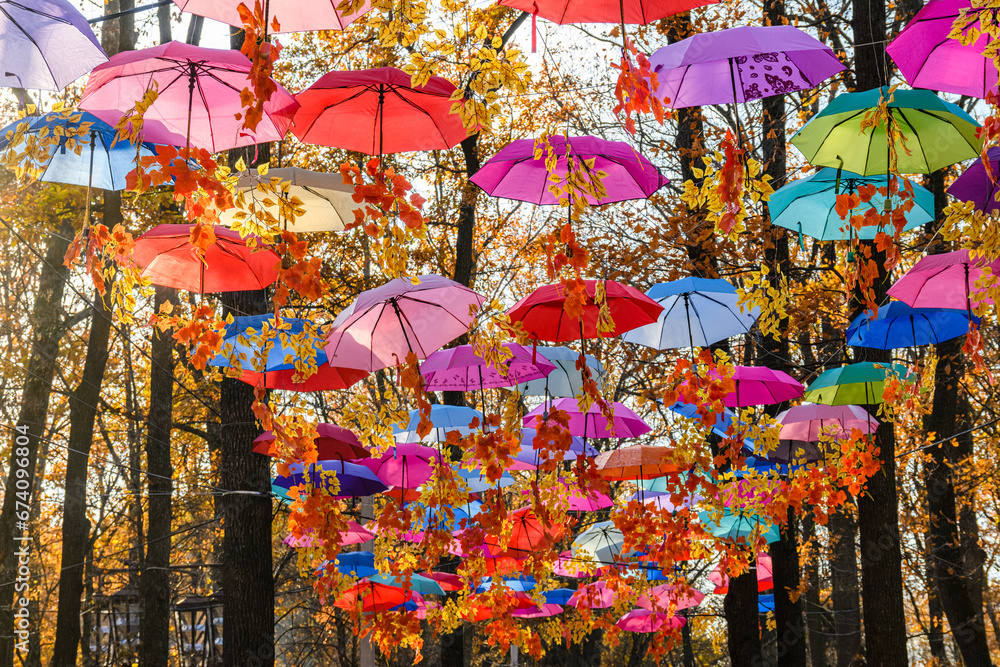 Many open umbrellas hanging above the head in city park