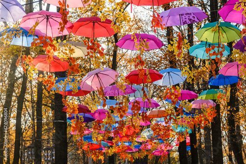 Many open umbrellas hanging above the head in city park © ihorbondarenko
