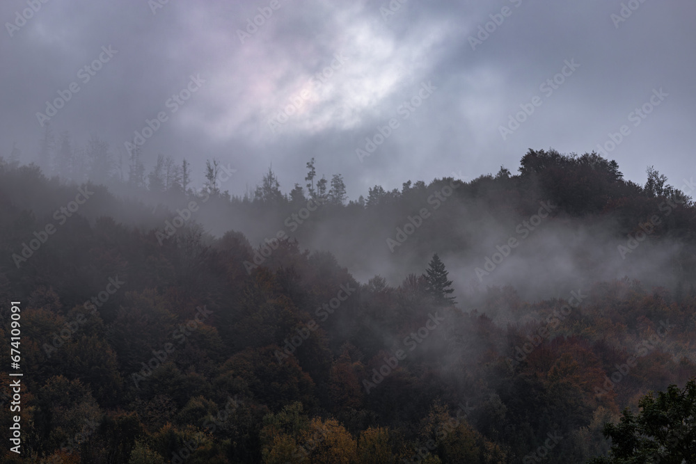 Silhouette of dark mountains and forest in mystical landscape. Mystical landscape. Fog in the mountains. Silhouettes of mountains. Morning mist in the forest among the hills. Gloomy mood.