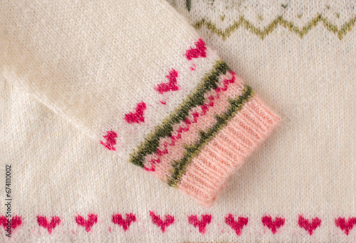 Warm woolen Christmas sweater sleeve with red hearts. Close up. Flat lay. Funny Christmas concept.